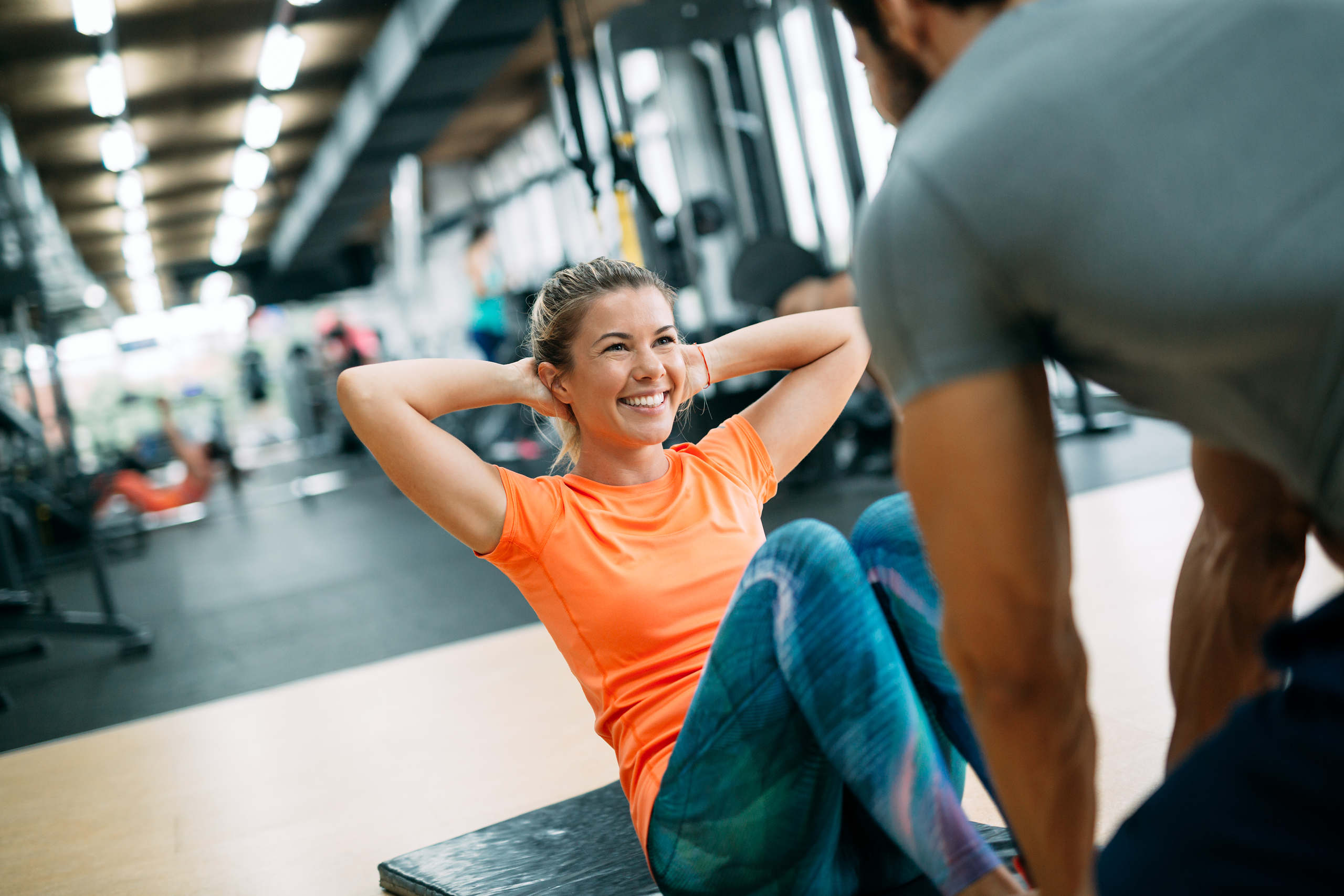 Personlig tränare hjälper kvinna i gymmet med träning.