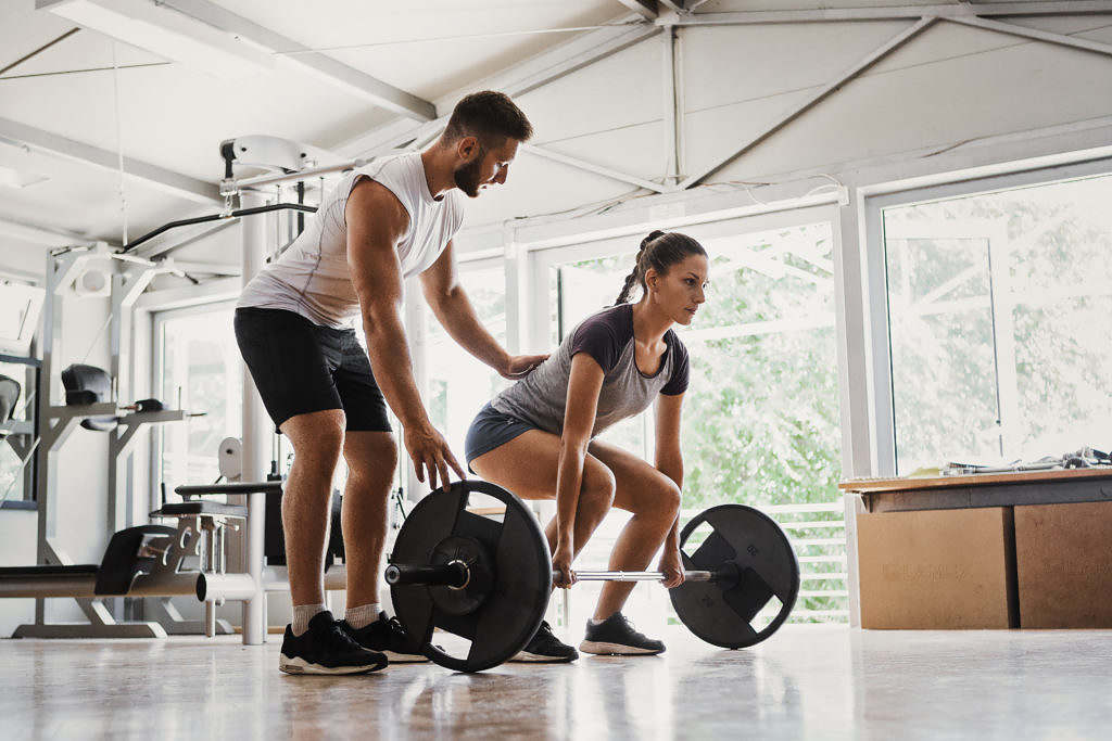 Professionell kroppsbyggare lyfter vikter med fitnessinstruktör.